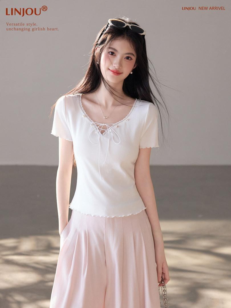 Model wearing a white lace-up short sleeve top with light pink wide-leg pants