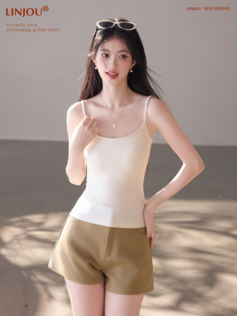 Model wearing a cream tank top and tan shorts