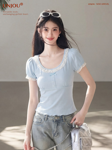 Model wearing a light blue lace-trim short-sleeve top with jeans