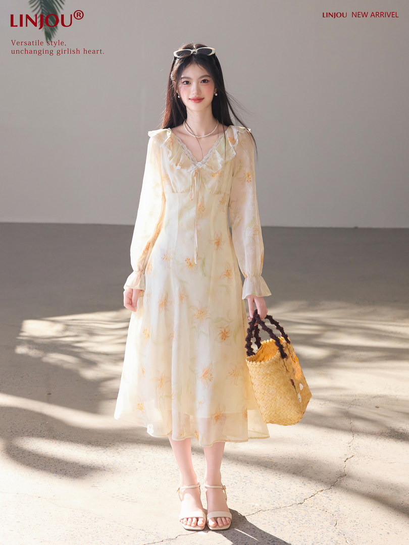 Model wearing a light yellow floral midi dress with long sleeves and a straw bag