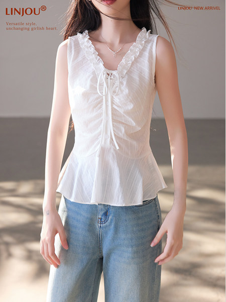 Woman wearing a white ruffled sleeveless top with blue jeans