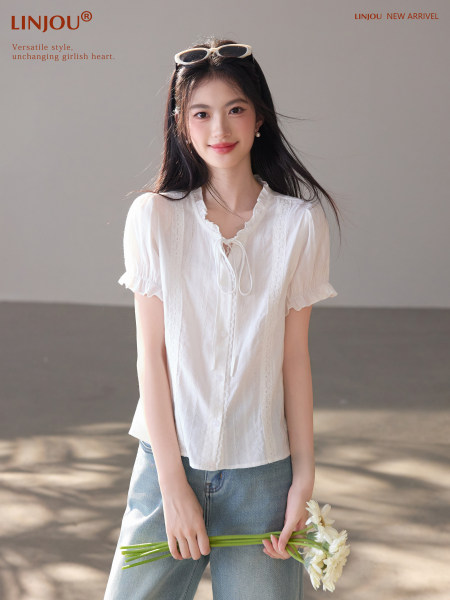 Model wearing a white short-sleeve ruffled blouse with jeans