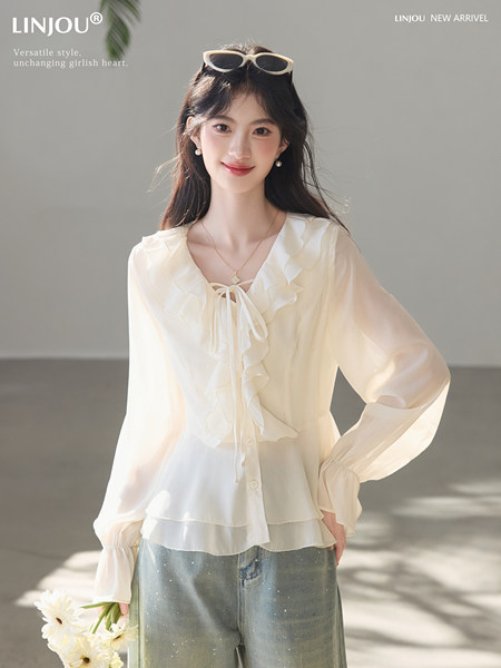 Model wearing a sheer white ruffled long-sleeve blouse