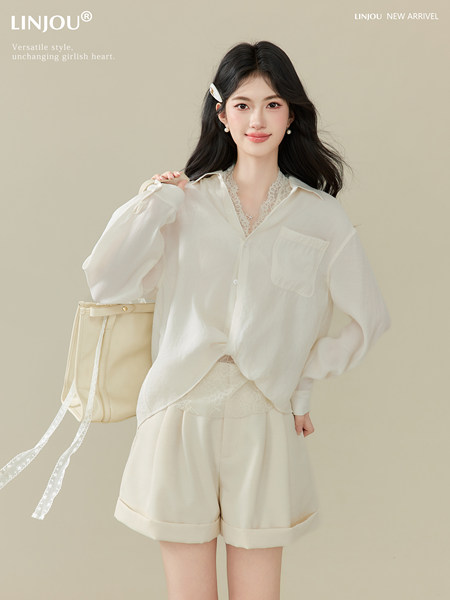 Woman modeling a cream white blouse and matching shorts set with a handbag