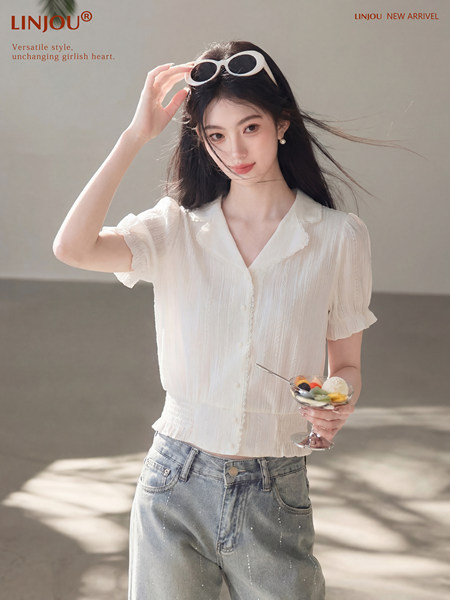 Model wearing a white short-sleeve blouse with light blue jeans