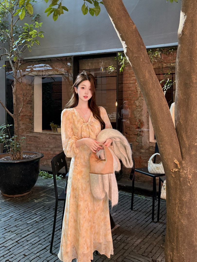 Woman wearing a long tie-dye dress and holding a small handbag outdoors