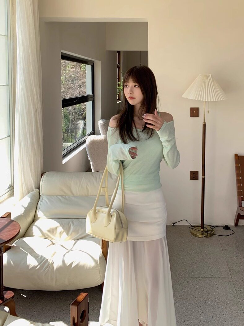 Woman modeling a mint off-shoulder top with a white maxi skirt and cream handbag