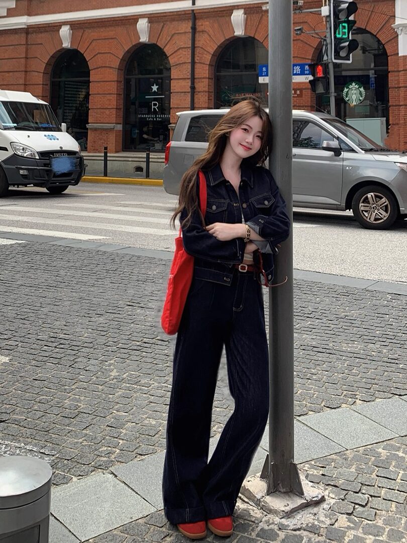 Woman wearing a dark denim jacket and wide-leg jeans on a city street