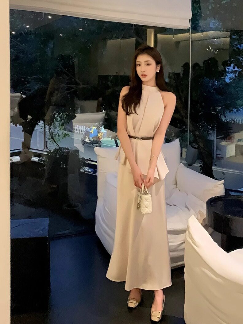 Woman wearing a sleeveless cream halter maxi dress with a belt