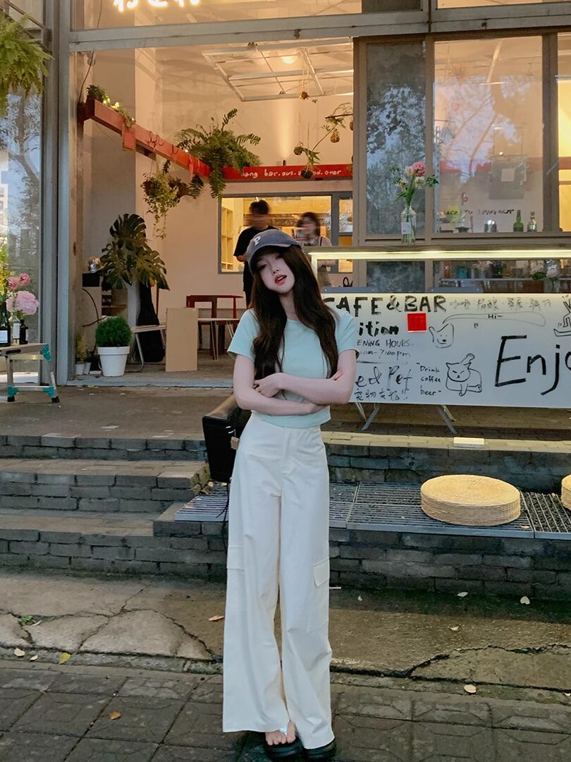 Woman wearing a light blue T-shirt and white wide-leg pants outdoors