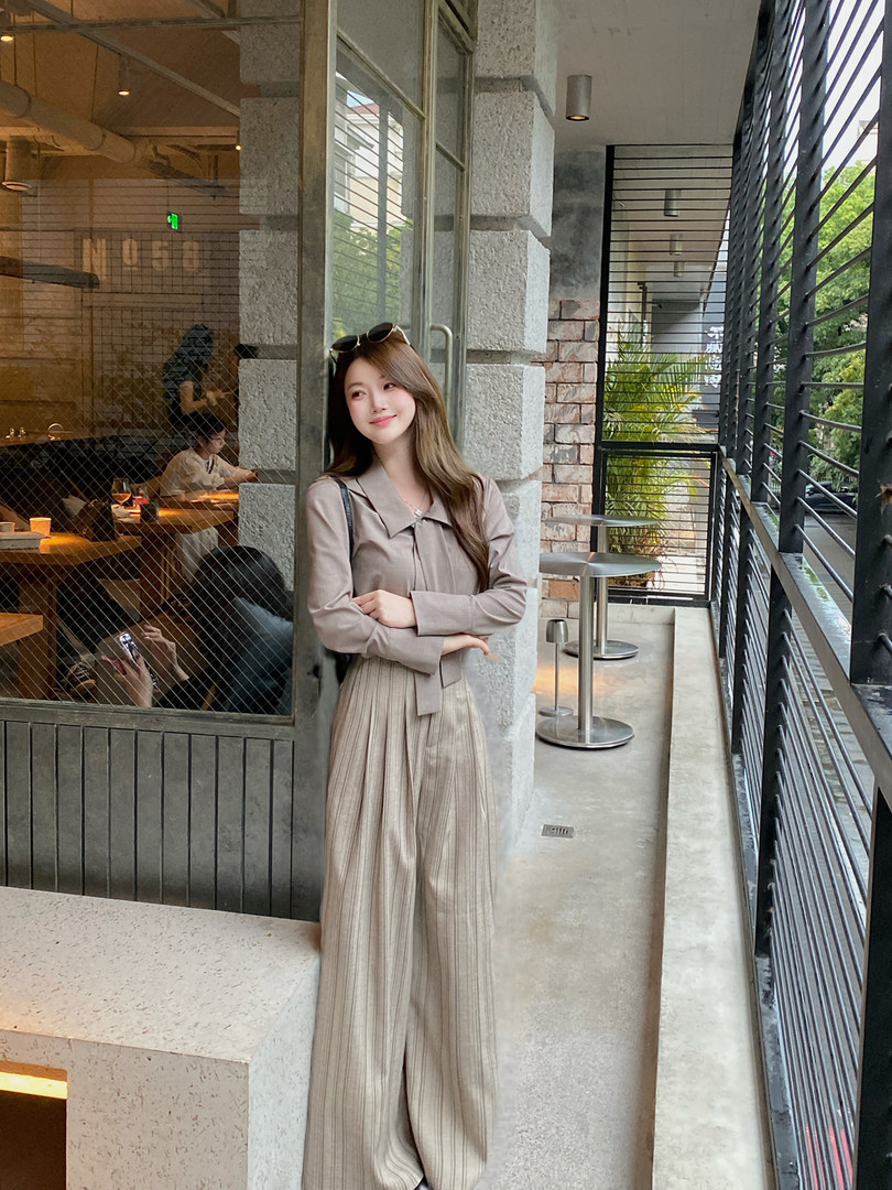 Woman wearing a beige long-sleeve top and wide-leg pleated pants