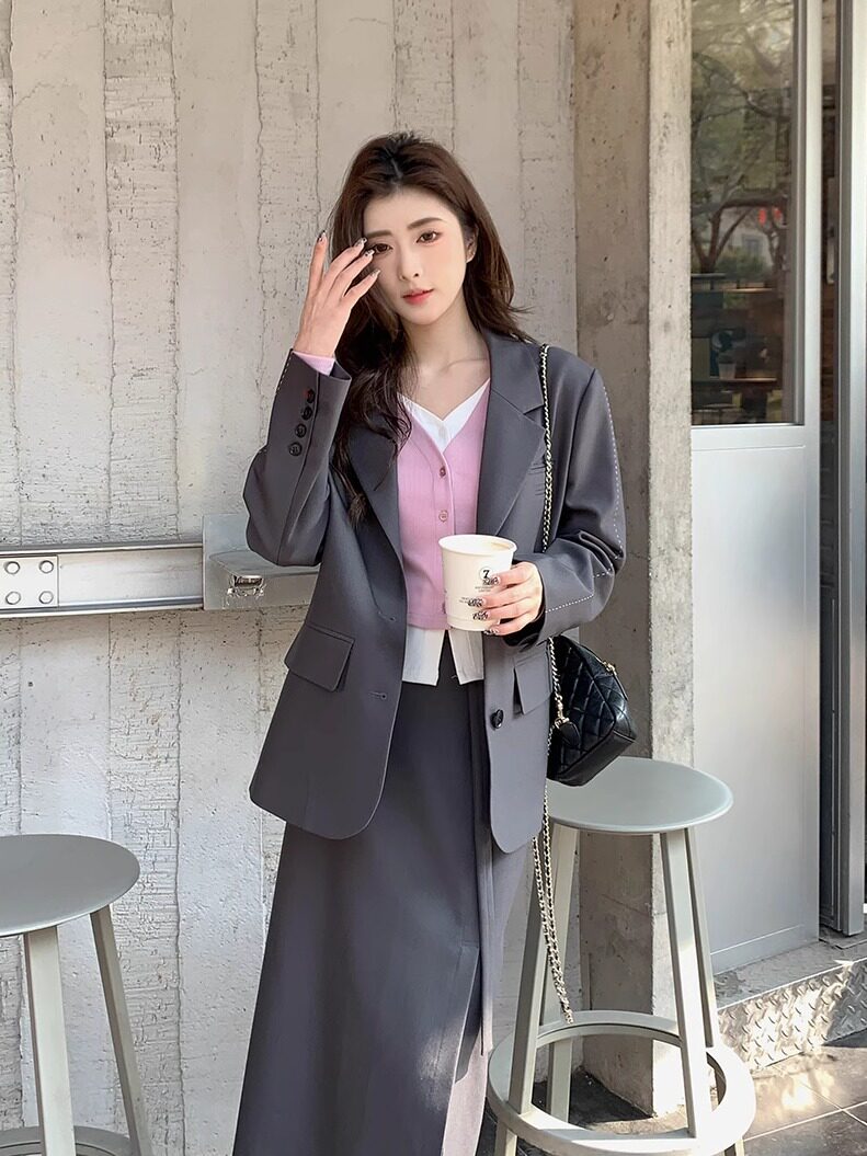 Woman wearing a gray blazer and matching long skirt outfit