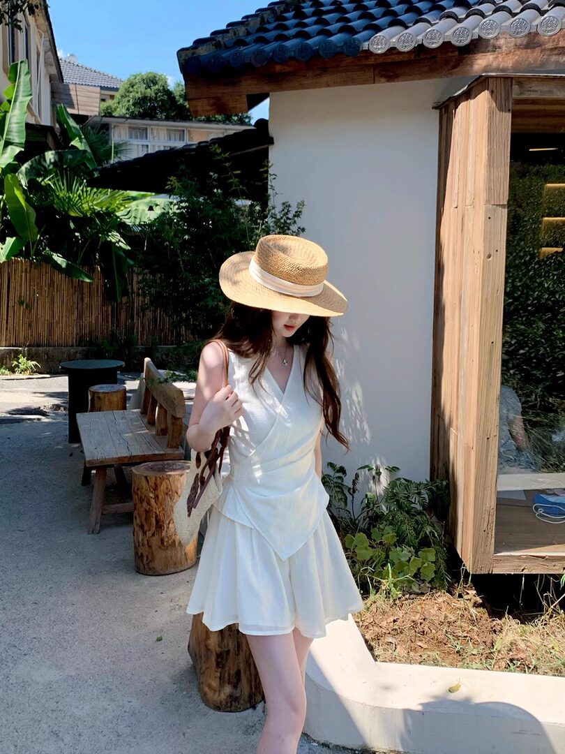 Woman wearing a white summer dress and straw hat outdoors