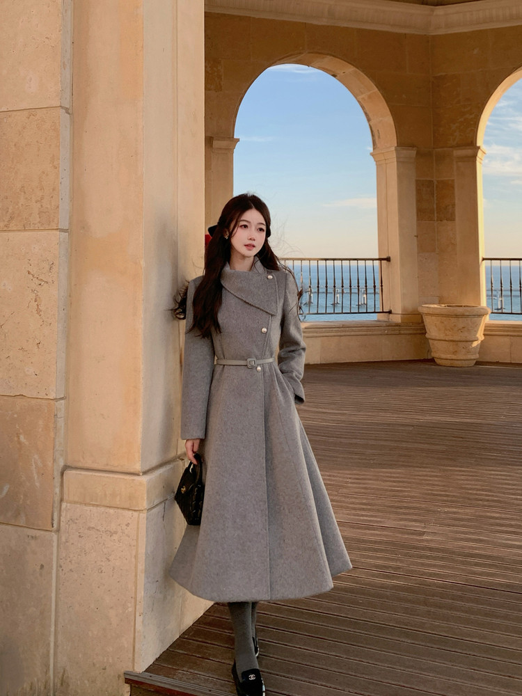 Woman wearing a long gray belted coat outdoors