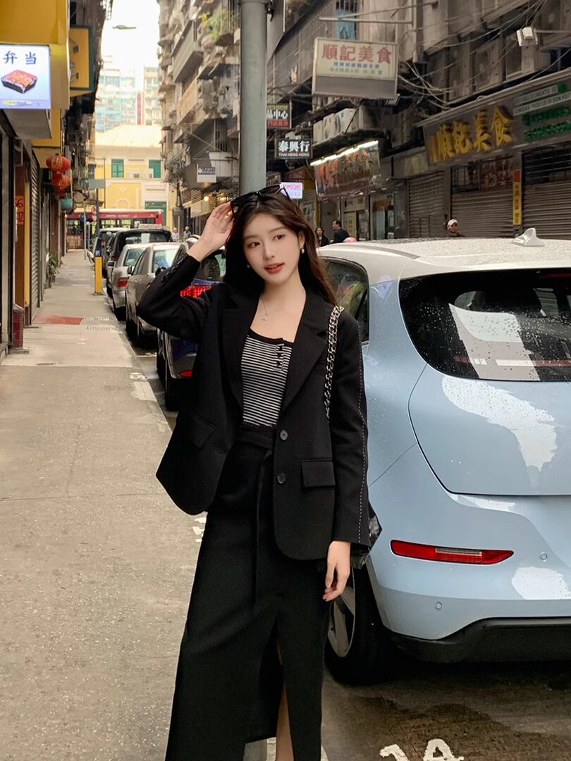 Woman wearing a black blazer and matching skirt with a striped top in a street setting
