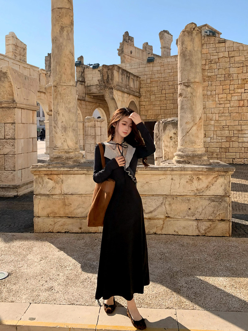 Woman wearing a black long-sleeve maxi dress with a contrasting gray collar and bow detail