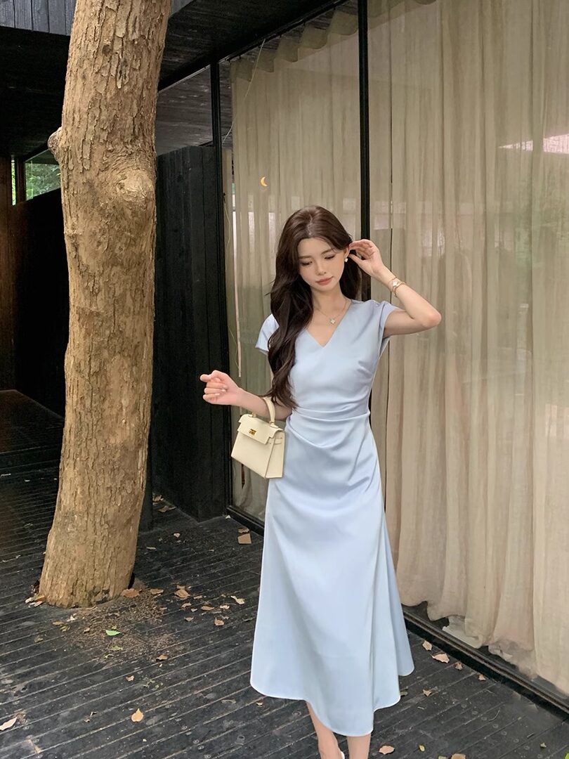 Light blue midi dress worn by a model with a small cream handbag