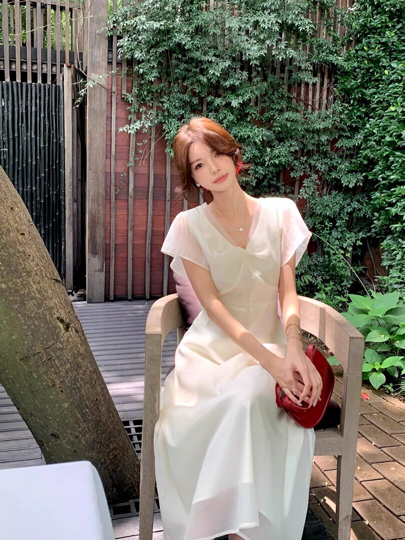 Woman wearing a white short-sleeve V-neck dress outdoors