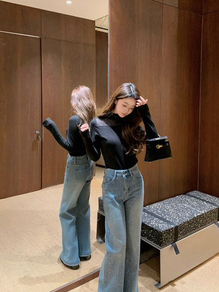 Woman wearing a black long-sleeve top and wide-leg blue jeans in a mirror selfie