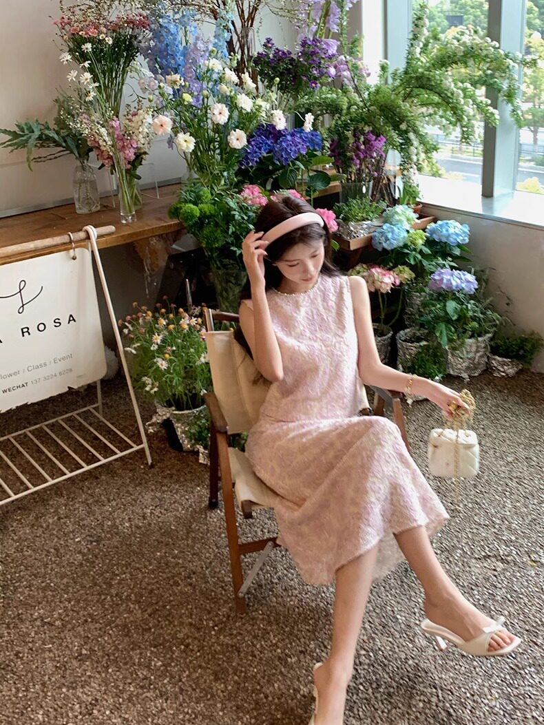 Woman wearing a light pink sleeveless dress seated in a flower shop