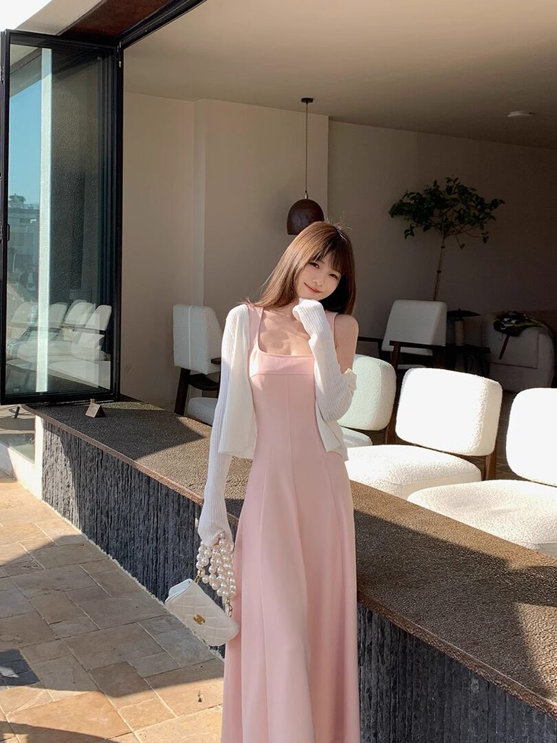 Pink sleeveless maxi dress worn with a white cardigan and small handbag