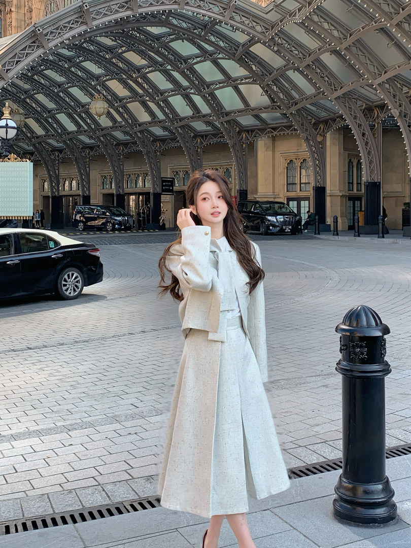 Woman wearing a cream-colored tailored coat and skirt set outdoors