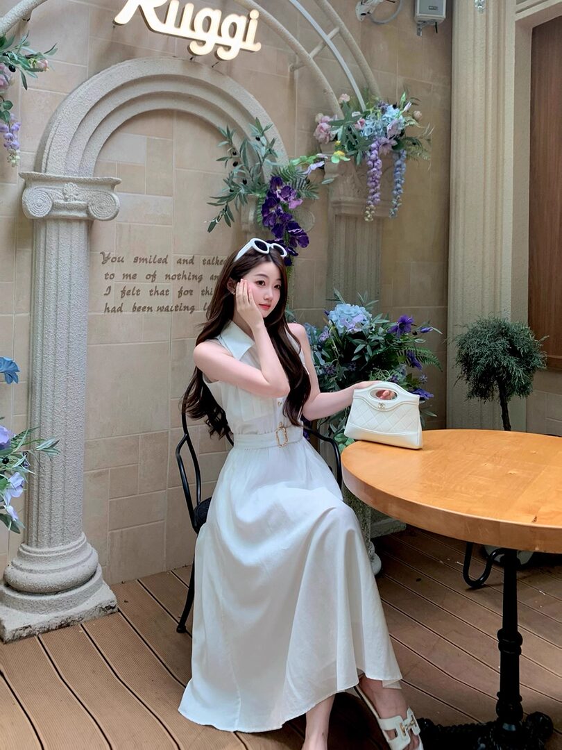 White sleeveless maxi dress worn by a woman holding a white handbag
