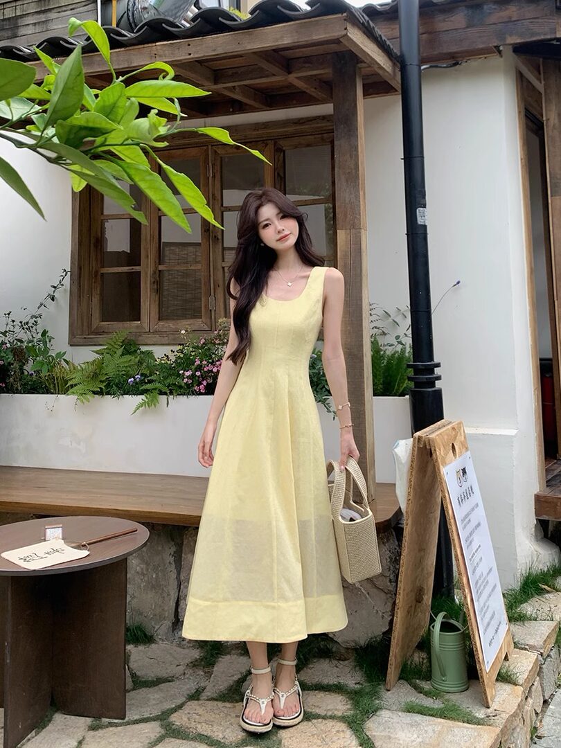 Woman wearing a pale yellow sleeveless midi dress outdoors