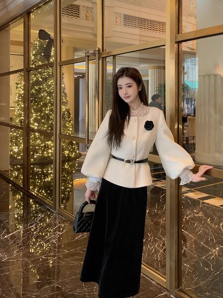 Woman wearing a cream embellished jacket with black skirt and handbag