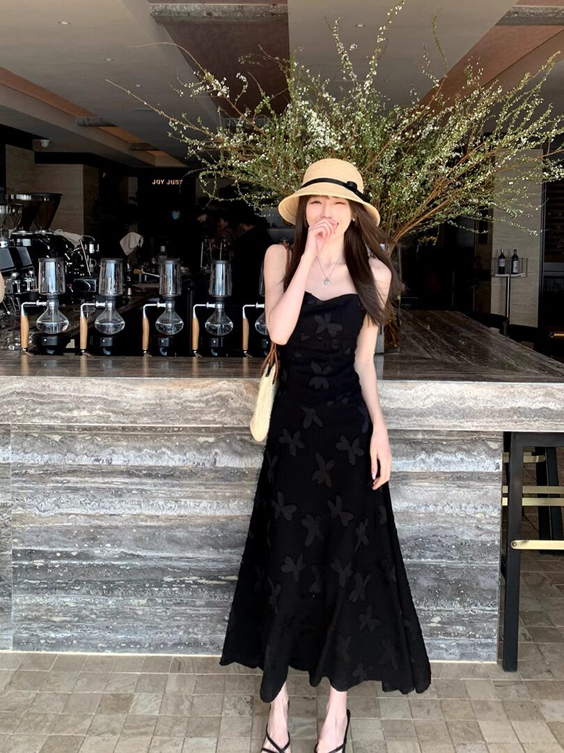 Black strappy midi dress with subtle floral pattern worn by a model