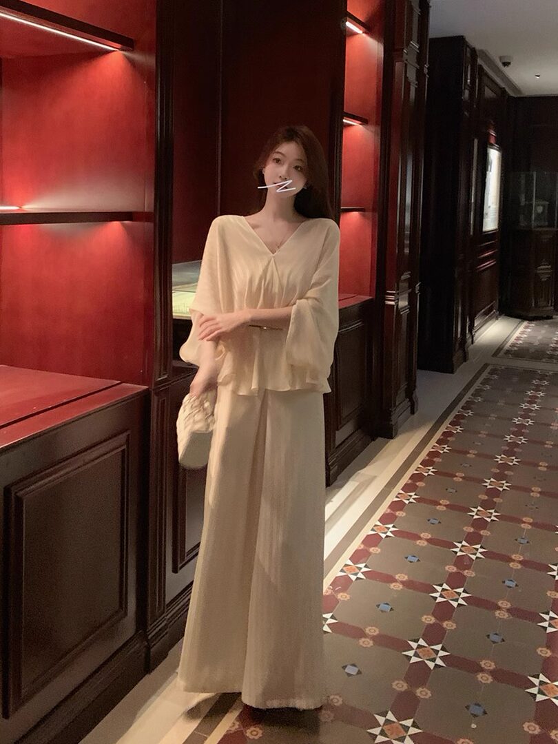 Woman wearing a beige flowy two-piece outfit with wide-leg pants