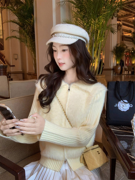 Woman wearing a cream fuzzy winter outfit with a matching hat and small handbag
