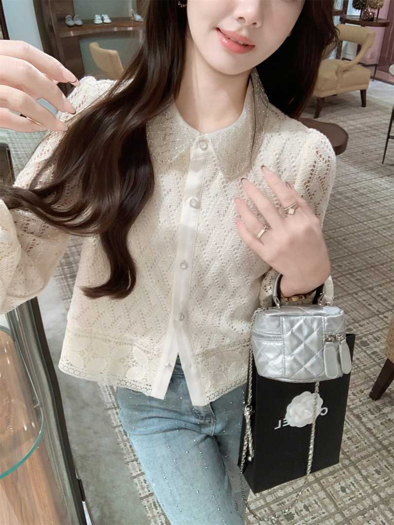 Woman wearing a cream lace blouse with jeans and a silver handbag