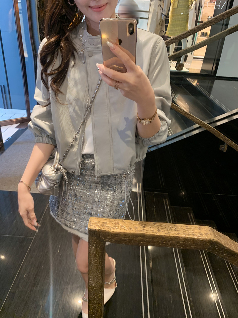 Woman wearing a light gray jacket with a silver sequin mini skirt