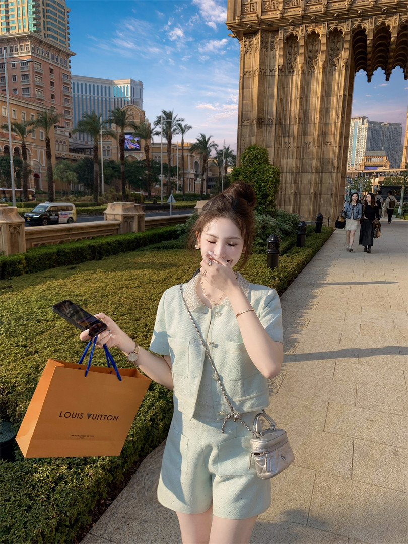 Woman wearing a light mint two-piece outfit with a small silver handbag outdoors