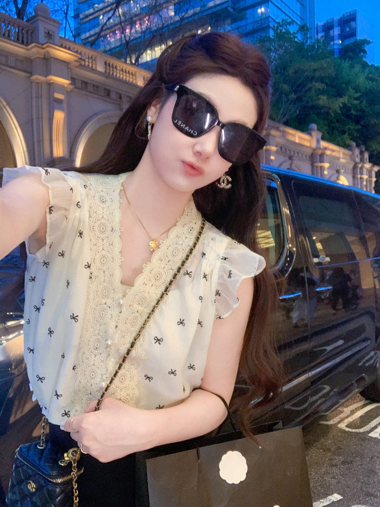 White lace-trim sleeveless blouse with bow print worn by a model