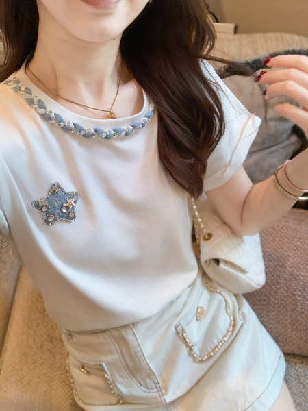 Woman wearing a white short-sleeve embellished top and light skirt
