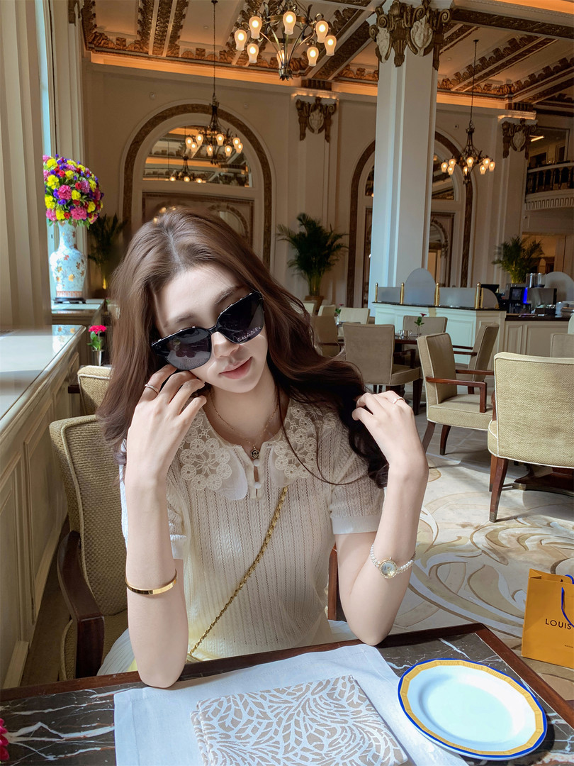 Woman wearing a cream lace dress/top with sunglasses in a luxury restaurant
