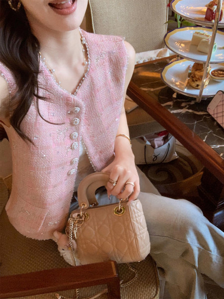 Pink textured tweed vest worn by a model, paired with a handbag