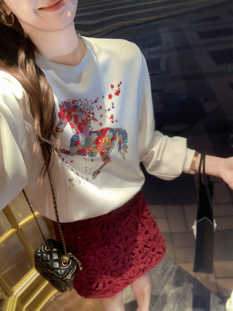 Model wearing a white graphic sweatshirt with a burgundy lace mini skirt and black quilted mini bag