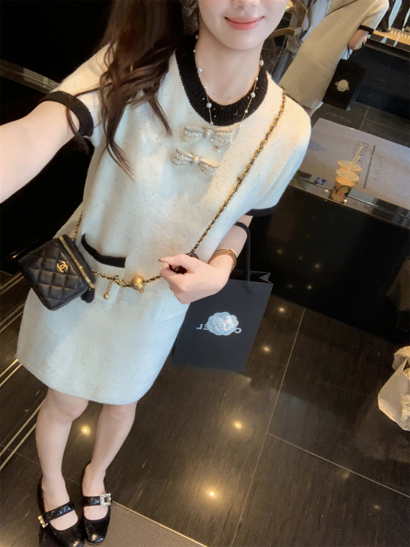 Woman wearing a cream mini dress with black trim and bow details