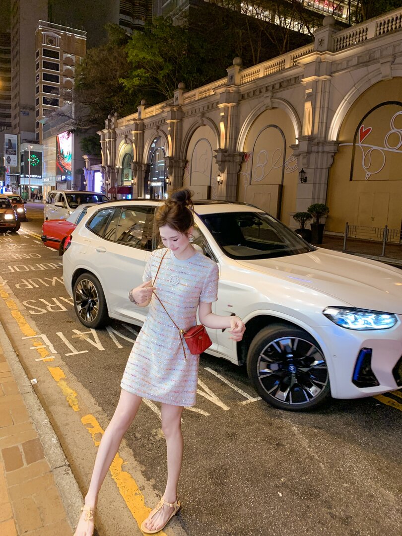 Woman wearing a light-colored short dress and sandals on a city street at night