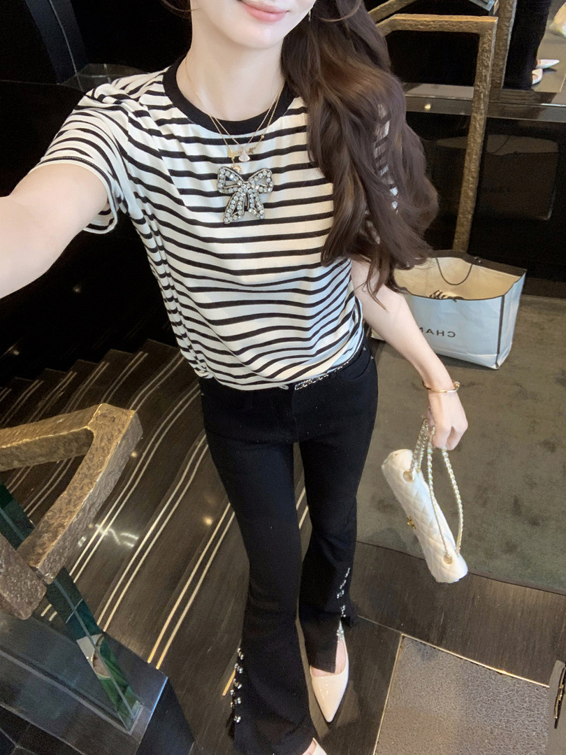 Woman wearing a black-and-white striped top with black pants and accessories in a mirror selfie