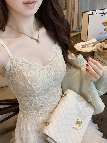 Woman wearing a white lace dress with a quilted white handbag