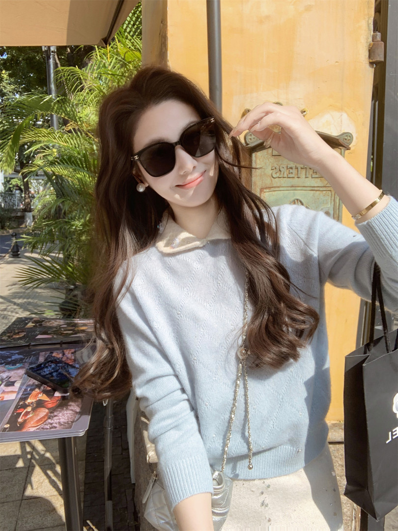 Woman wearing a light blue sweater with sunglasses outdoors