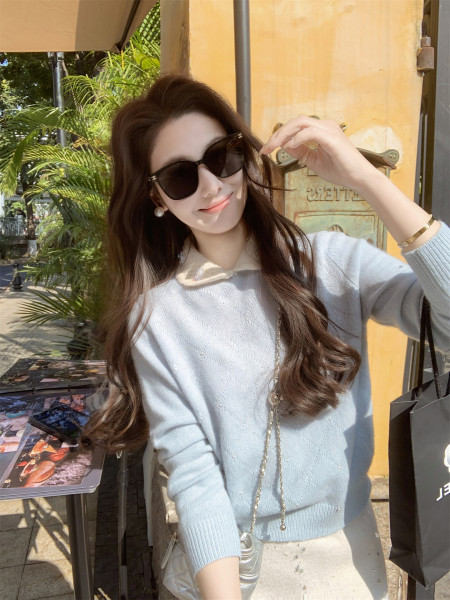 Woman wearing a light blue sweater with sunglasses outdoors