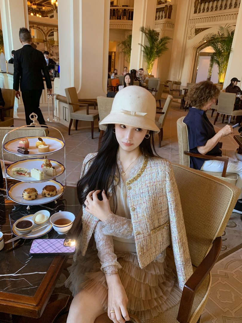 Woman wearing a cream hat and elegant lace-and-tulle outfit at a tea room