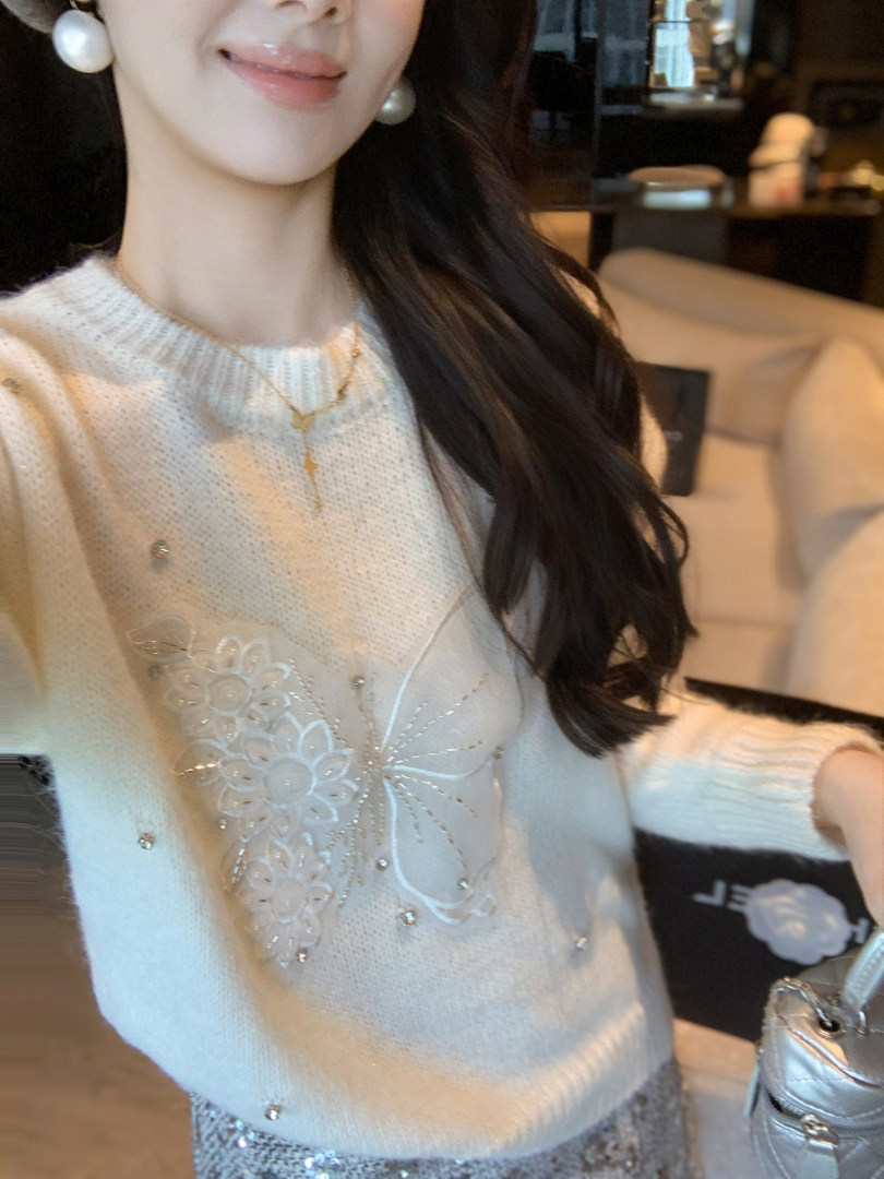 Woman wearing a white knit sweater with floral embellishments