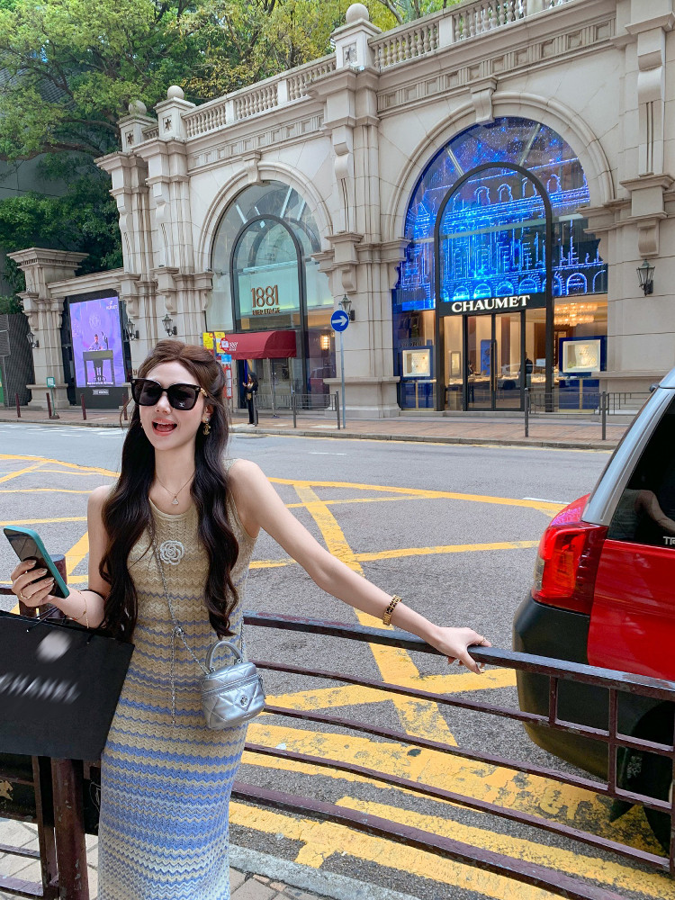 Woman wearing a sleeveless knit dress and carrying a small silver handbag on a city street