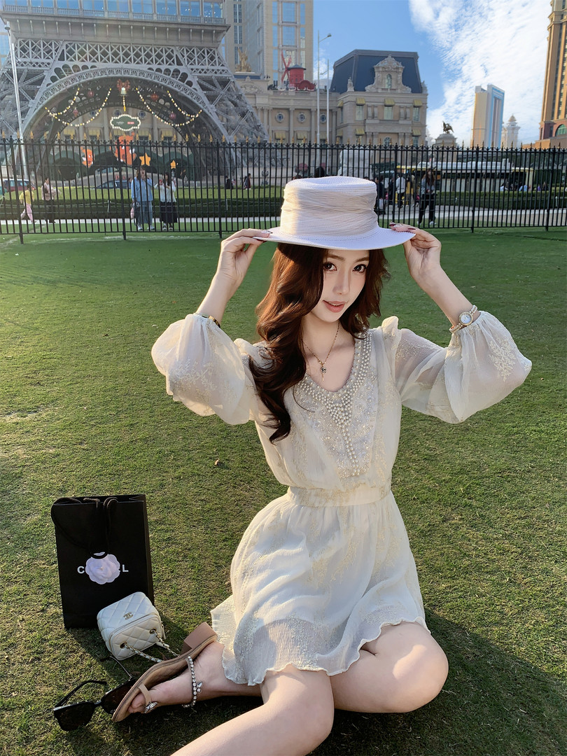 Woman wearing a white sheer dress and wide-brim hat outdoors